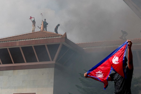 Manifestantes comemoram com bandeira do Nepal após entrar em complexo do Parlamento nepalês durante protesto contra o governo em 9 de setembro de 2025
